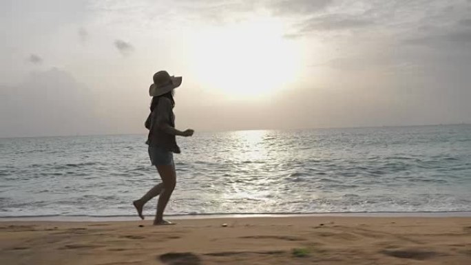 年轻的亚洲妇女在日落时在海滩上奔跑