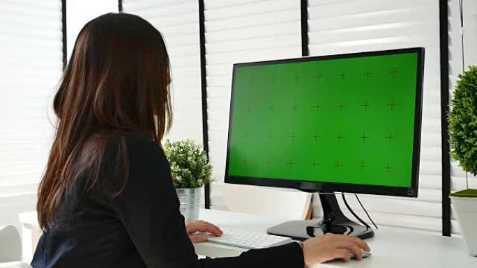 女商人在办公室使用带有绿屏的计算机