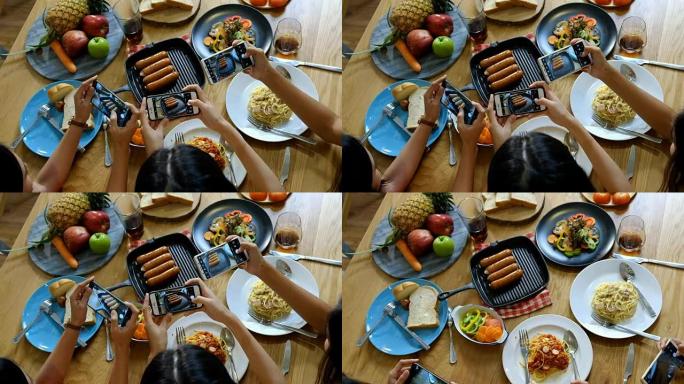 有吸引力的年轻亚洲女士在社交媒体上拍照，并在意大利美食，香肠和沙拉中享用午餐