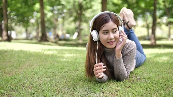 年轻女子躺在草地上听音乐