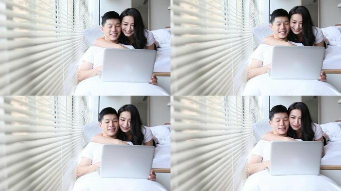 夫妇在床上使用笔记本电脑浏览互联网