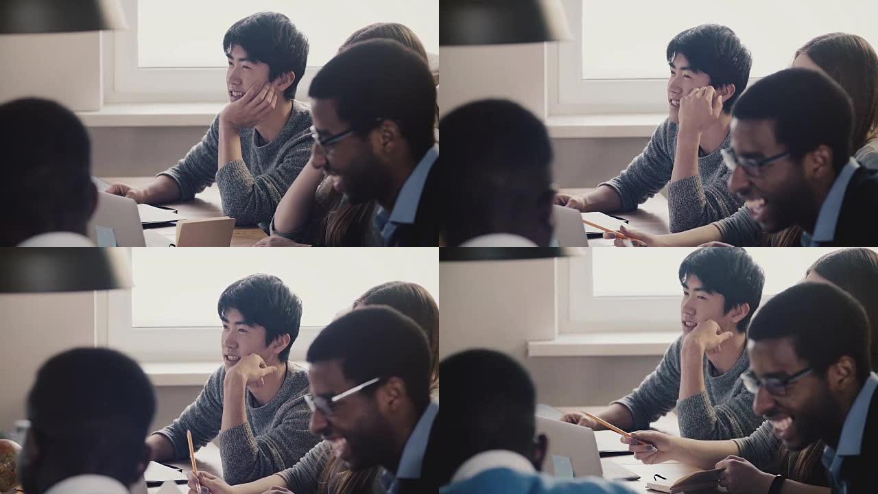 特写快乐的日本年轻员工在多民族办公室会议上与同事一起倾听和大笑