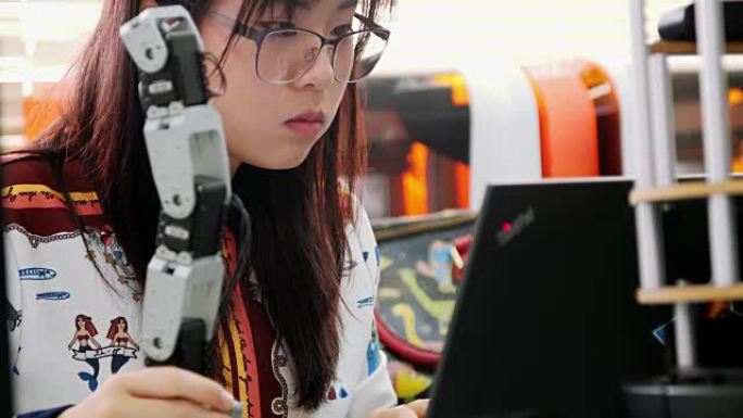 青少年为她的学校机器人俱乐部项目在一个功能齐全的可编程机器人上工作。创意设计师在车间测试机器人原型。