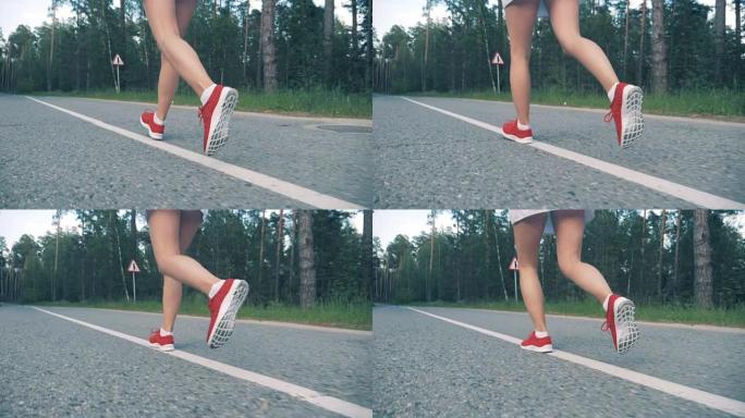 穿着运动鞋的年轻女士正在慢动作地沿着森林公园奔跑。女运动员慢跑。
