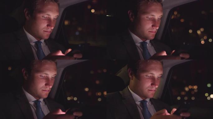 年轻的商人晚上在繁忙的城市的汽车后座上用手机发短信
