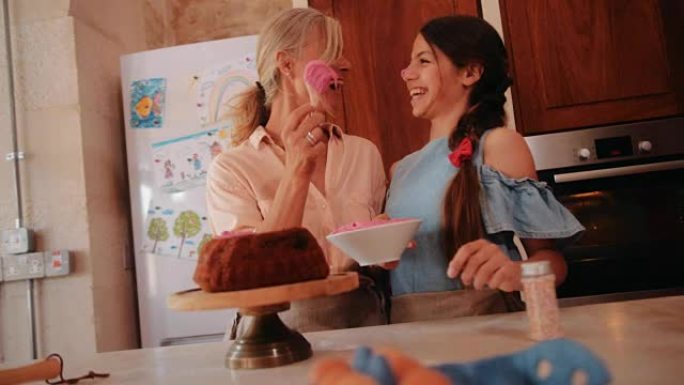 祖母和孙女在厨房里为自制蛋糕锦上添花