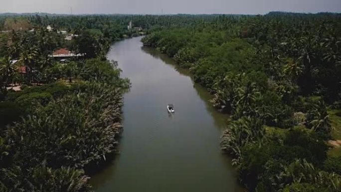 无人机在美丽的宽阔河流上的小船上向前飞行，在热带绿树丛中的丛林荒野中流动
