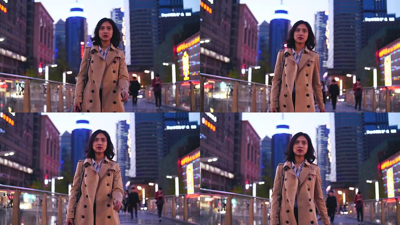 一个相当快乐的年轻亚洲女人晚上在城市街道上行走的慢动作