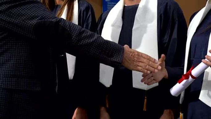 近距离拍摄一位面目全非的院长与毕业于博士学位的学生握手