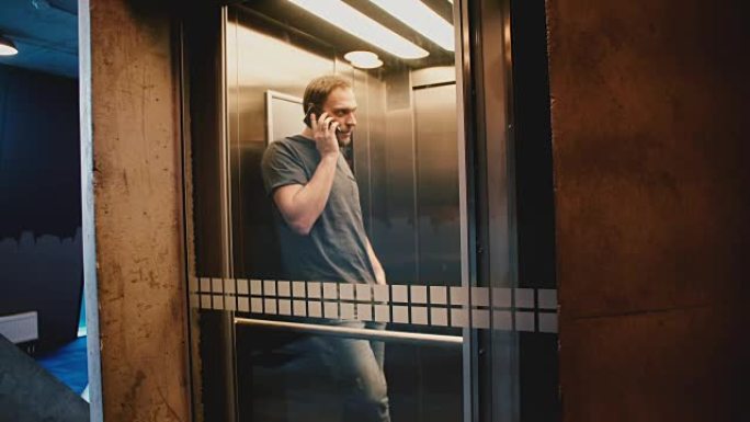 年轻快乐的商人坐在透明的玻璃电梯里打电话，门打开，他走了出去
