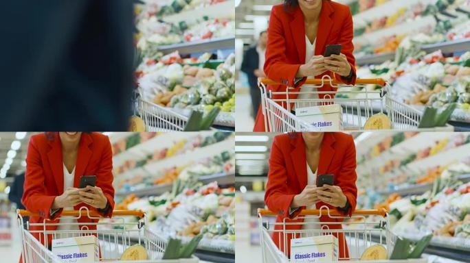 在超市: 女人使用智能手机，靠在商店新鲜农产品区的购物车上。在大商场里，女人在手机上浏览互联网。慢动
