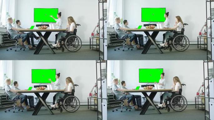坐在轮椅上的年轻女子和她的展示团队与他们的导师讨论。创业公司