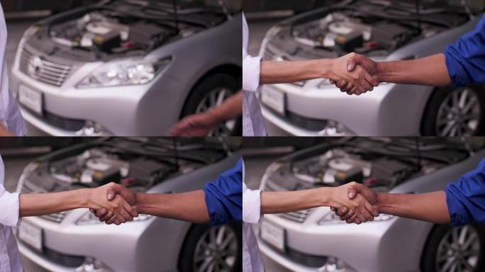 在汽车维修店，汽车服务概念中，机械师和客户握手的特写镜头