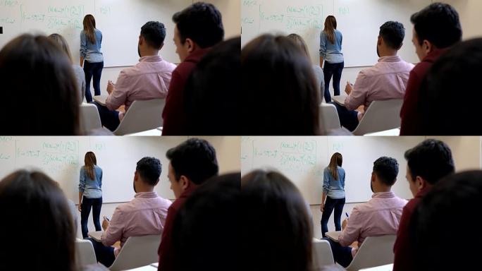 无法识别的女学生在板上写公式和其他学生注意
