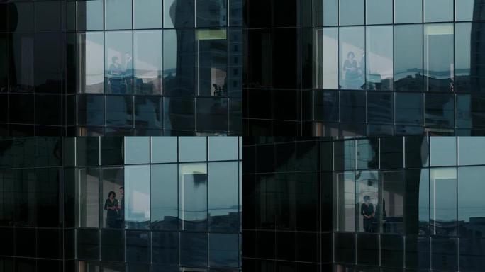 摩天大楼外的航拍镜头: 商人和女商人站在办公室的窗户上谈论生意。金融商务区和在大城市工作的商人的飞行