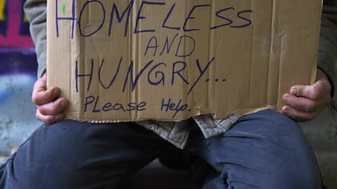 高清: 无家可归的人跪着纸板标志