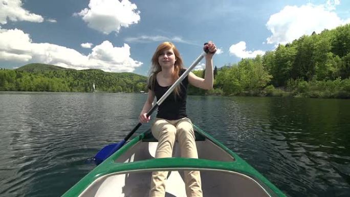 一名年轻女子在山坡上的湖面上划独木舟