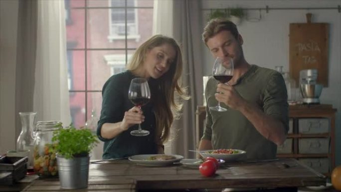 夫妻俩在厨房里吃着自制的食物，喝着葡萄酒