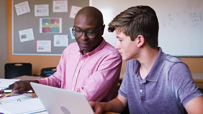 高中导师给男学生在办公桌上使用笔记本电脑一对一的学费