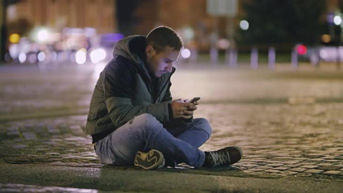 DS年轻人晚上在城市使用智能手机