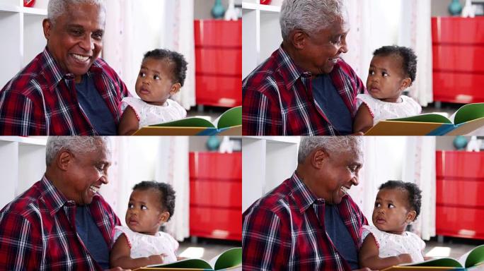 祖父坐在家里和小孙女一起看书 -- 慢动作拍摄