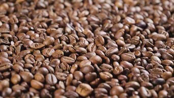 一只手触摸一把咖啡豆的特写镜头，以闻到气味和一致性。优质咖啡仍然热气腾腾。