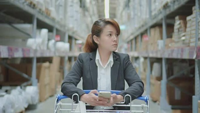 亚洲女性在现代仓库中使用智能手机，慢动作