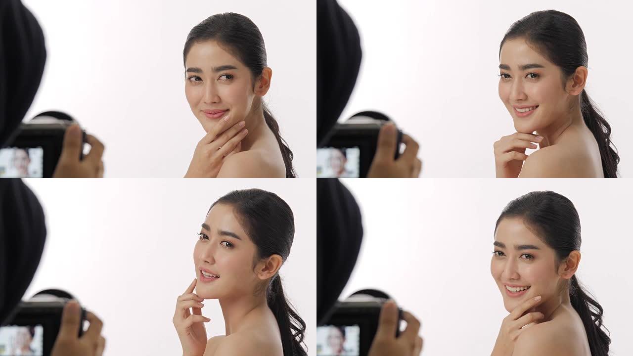 幕后拍摄的美丽的年轻亚洲女性模特，美丽的脸和完美的皮肤被记录在白色背景的摄像机上。
