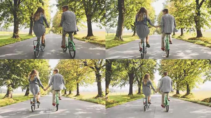 TS年轻夫妇在绿树成荫的道路上骑自行车