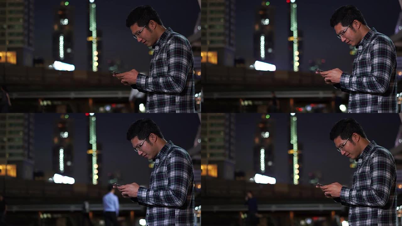 4k分辨率亚洲男子晚上站在智能手机上打字