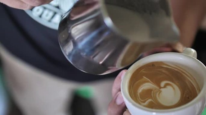 咖啡师在一杯咖啡中加入泡沫牛奶，用于泡沫艺术