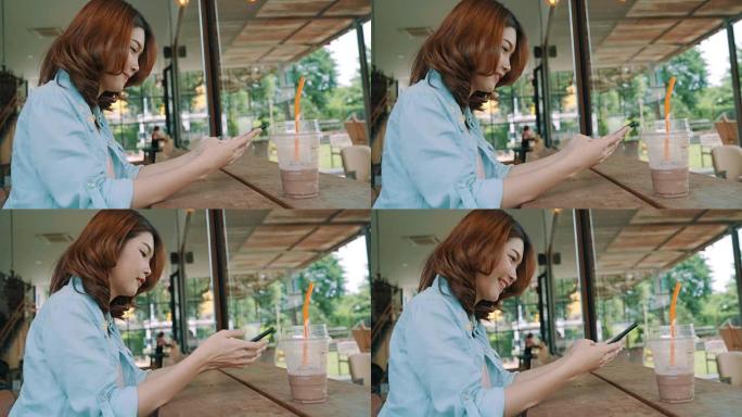 快乐快乐的亚洲年轻女子坐在咖啡馆喝冰绿茶，使用智能手机聊天、阅读和发短信。女性生活方式概念。
