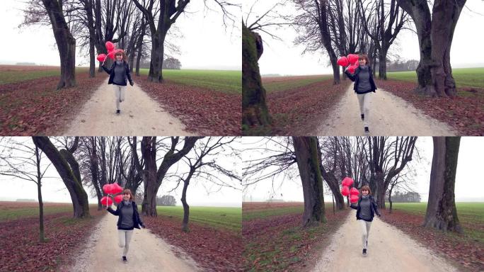 女孩带着红色心形气球在公园里奔跑