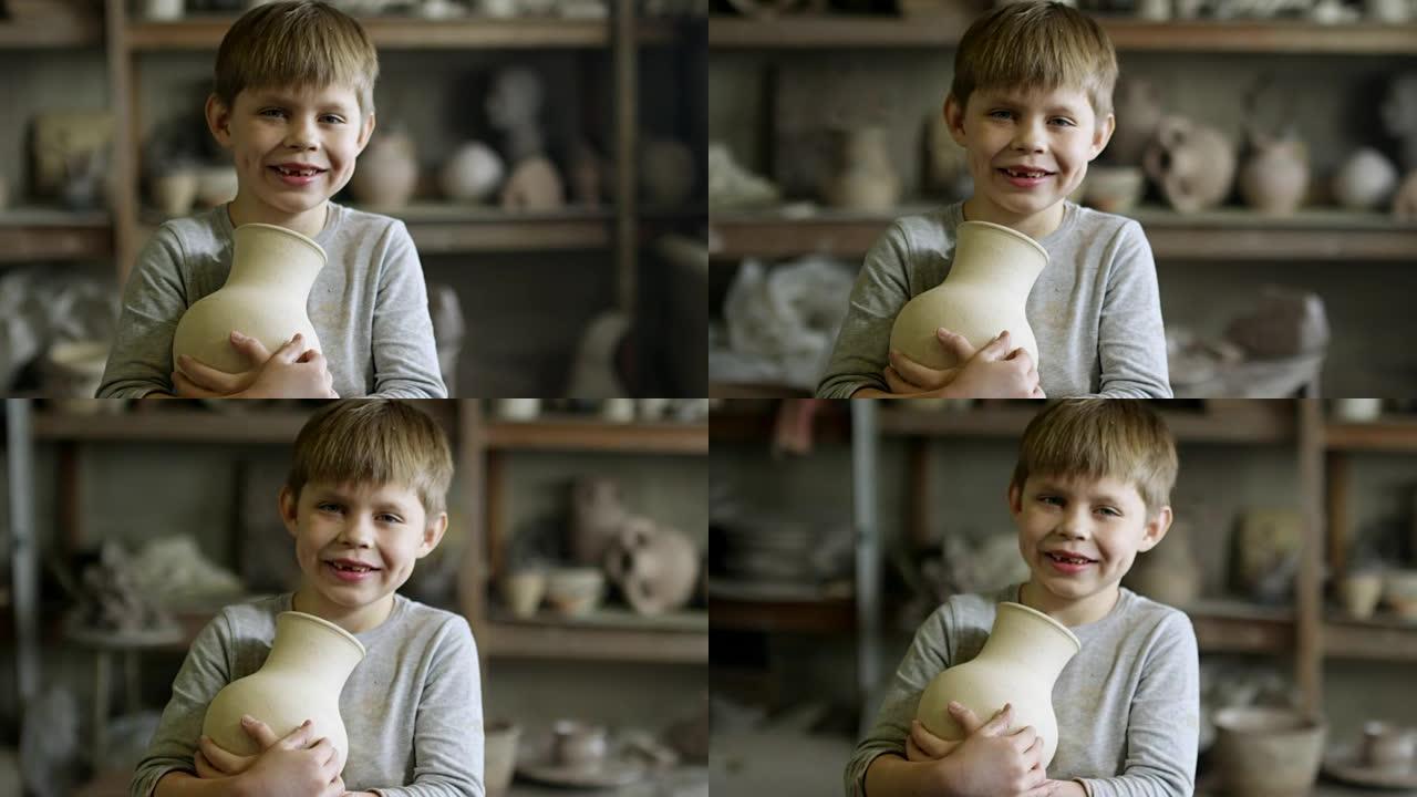 男孩与陶瓷花瓶在陶器车间摆姿势