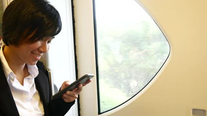4K: 在火车上使用智能手机的女商人，窗户一侧