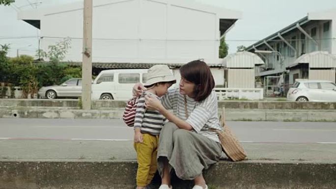 亚洲母亲和孩子坐在人行道上玩耍。