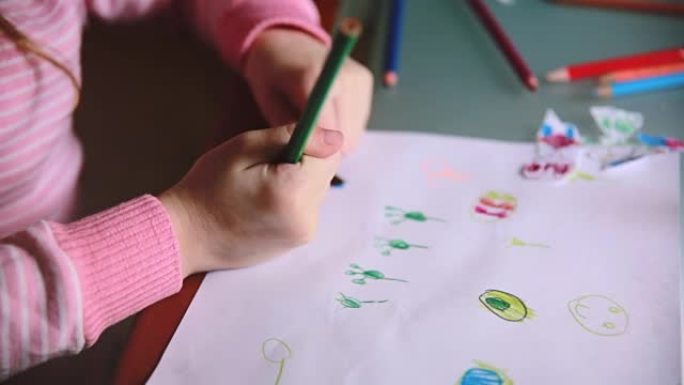 摄像机在小高加索学龄前女孩的手上滑动，用五颜六色的铅笔在桌子上画动物特写