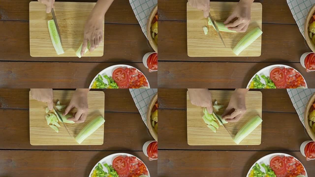 女酋长在厨房的切菜板上制作沙拉健康食品和切碎黄瓜的俯视图。