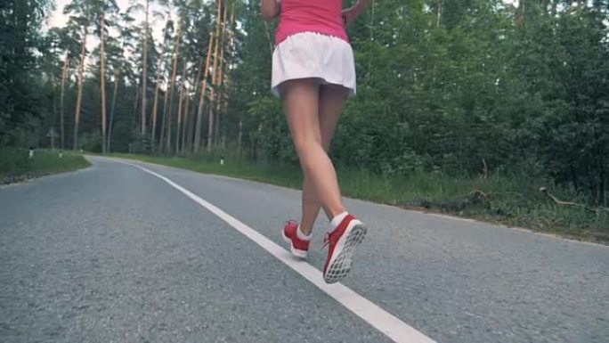 森林路，一位年轻女士的腿沿着它慢跑。稳定，慢动作。