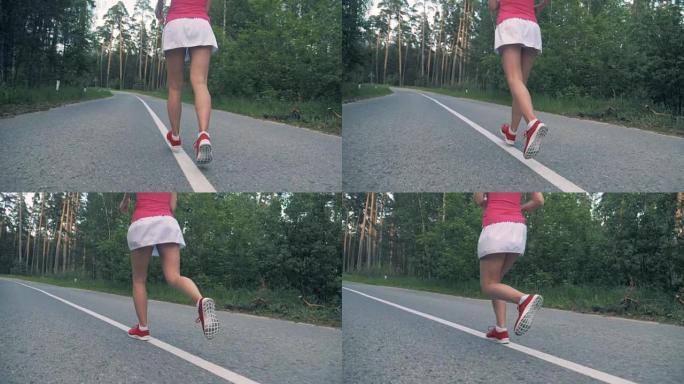 森林路，一位年轻女士的腿沿着它慢跑。稳定，慢动作。