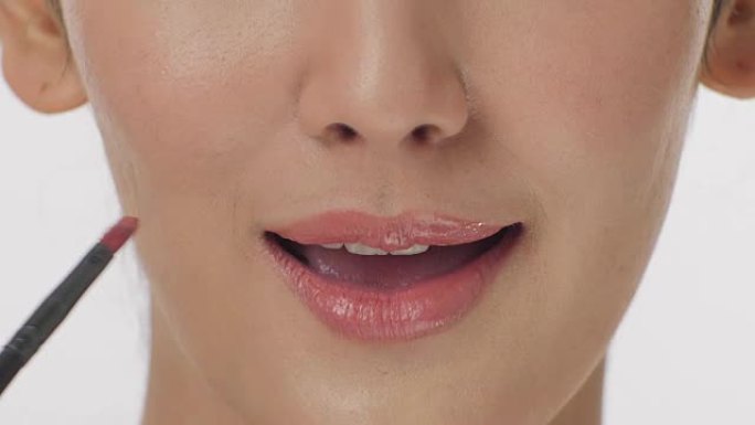 化妆师在性感嘴唇上涂口红的特写肖像有魅力的女人。化妆嘴唇。美丽和时尚概念。
