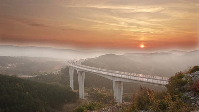 日落时分，车辆在高架桥上飞驰而过，薄雾笼罩