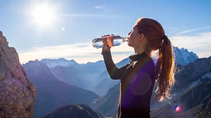 年轻女子在山顶喝水