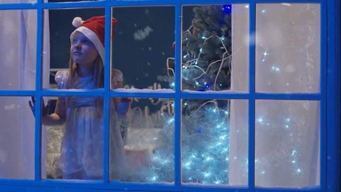 戴着圣诞老人帽子穿过窗户的迷人女孩
