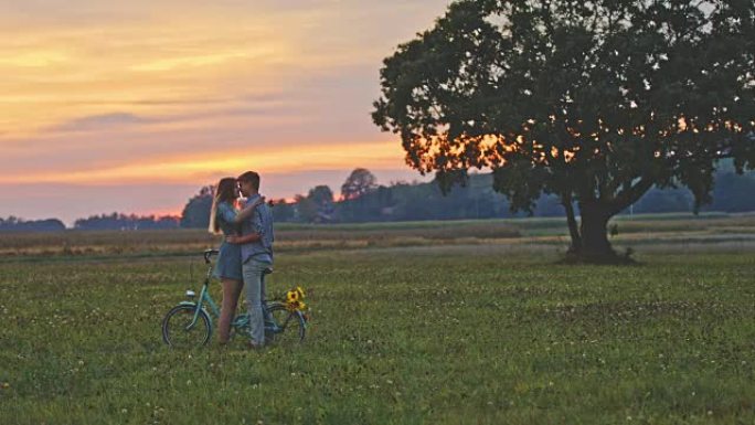 DS年轻夫妇在日落时骑自行车接吻