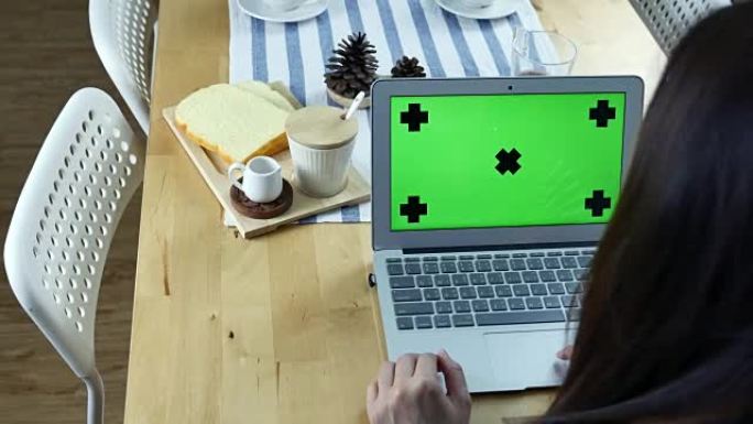 女人的肩膀视图，使用带早餐的绿屏笔记本电脑，色度键