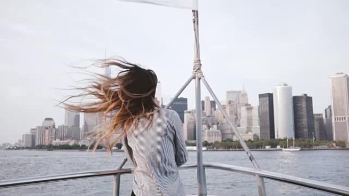 快乐兴奋的旅游女孩肖像，头发飞舞，从旅游船上慢动作欣赏纽约天际线的景色