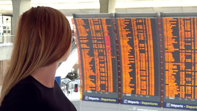 女人在机场看着飞机飞行信息板