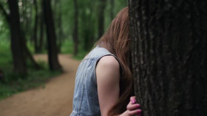 迷人的黑发女孩偷窥圆树干。