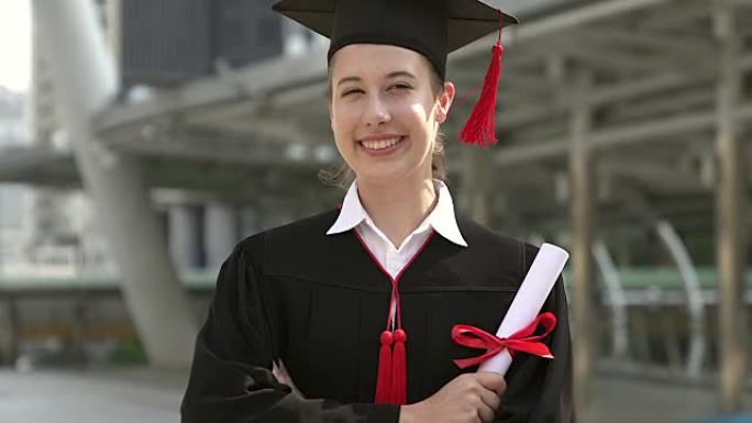 穿着学术服装的成功毕业生拿着文凭，对着镜头微笑。